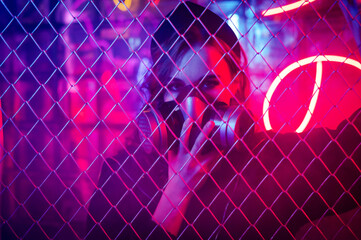 Caucasian woman in a gas mask behind a fence in a neon studio. 