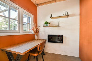 Minimalist interior of study room with parquet floor and orange walls furnished with table