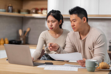 Concentrated korean husband and wife working on family budget