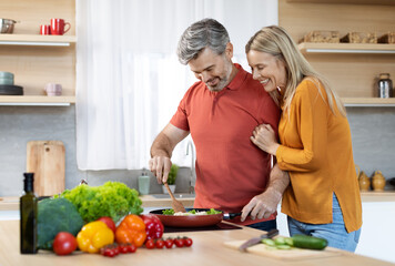 Loving middle aged husband cooking for his beautiful wife