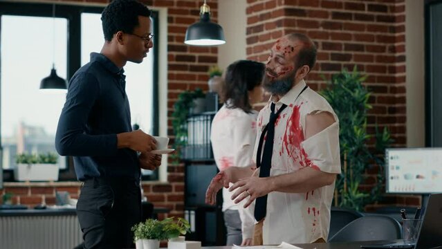 African american businessman discussing with infected brain-eating zombie colleague in office workspace. Dead walking corpse with deep and bloody wounds talking with doomsday survivor.