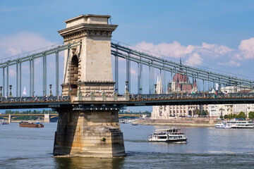 Een van de twee gewelfde stenen pilaren van de Széchenyi-kettingbrug met op de achtergrond het Hongaarse parlementsgebouw en de Margarethabrug - Boedapest, Hongarije