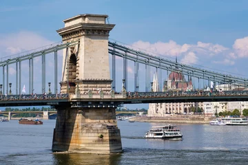 Selbstklebende Fototapete Kettenbrücke Einer der beiden gewölbten Steinpfeiler der Széchenyi-Kettenbrücke mit dem ungarischen Parlamentsgebäude und der Margaretenbrücke im Hintergrund - Budapest, Ungarn