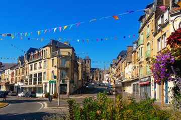 Summer view of Rethel cityscape during Feast of Assumption overlooking streets decorated with festive garland of small colorful triangular flags and Saint-Nicolas Church in background, France.
