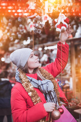 Happy girl chooses Christmas toys on the street market. High quality photo