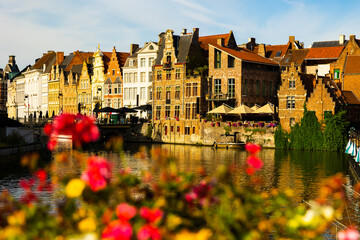 View of picturesque blooming area with typical residential buildings in historic center of Ghent city along Leie river on summer day, Belgium