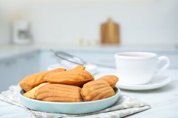 Tasty madeleine cookies on table in kitchen