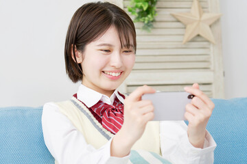 自宅でスマホで動画を見る高校生