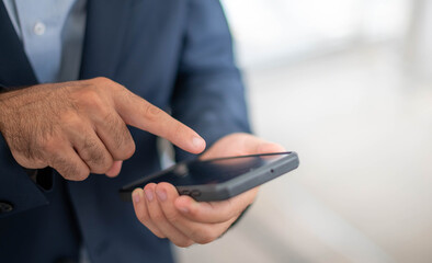Male hand touching and looking at a smartphone to search and find something to use, or prepare to pay with an e-payment system on his phone.