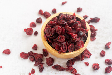 dried organic cranberry in wooden bowl on white table background.