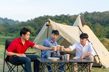 Young man are happy to camp on a lake with forests and mountains in the background.