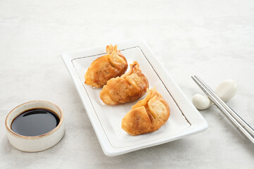 Gyoza, deep fried dumpling with juicy chicken and cabbage. Served in white plate with soy sauce
