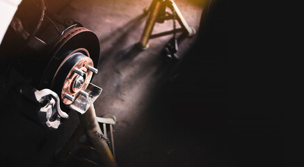 Automotive disc brake and caliper without wheel on jack stand in the auto repair garage , panoramic...