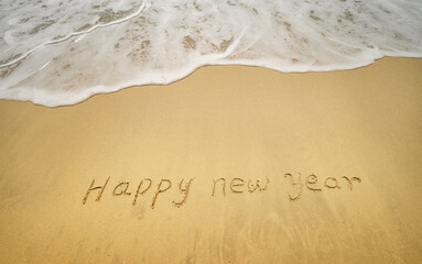 happy new year written in the sand