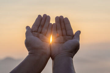 Hands praying to god on sunset sky background. Concept of religion faith