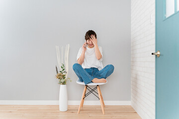 スマホで通話しながらショックを受けるアジア人女性（泣く・悲しい）
