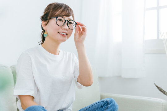 家でソファに座るメガネをかけたアジア人女性
