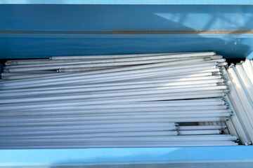 Heap of Uld used Fluorescent light tube lamps in dump trash, recycled electric waste. harmful substances. Discarded lamps