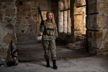 Obraz na płótnie Canvas Blonde woman in army uniform holding a firearm in an abandoned building. 