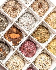 Candies in a white box made of dried fruits, without sugar and dyes. From natural ingredients. Contains dates, coconut, dried apricots, almonds, peanuts, figs, sesame and cocoa.