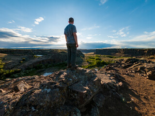 Fototapeta premium Athletic adventurous male hiker standing on a ridge looking down into a valley along the Columbia River.