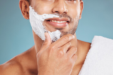 Man with shaving cream on face, beard maintenance and skincare for mens health and beauty treatment with blue background. Health, skin care and facial hair, morning shave bathroom routine with towel.