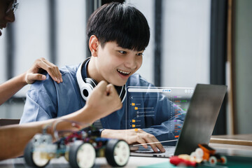 Asian teenager students doing robot arm and robotic cars homework project in house using computers...