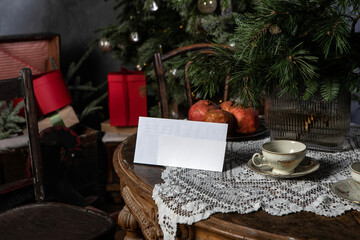 Table with white envelope and horizontal postcard flyer mockup in retro Christmas decorations