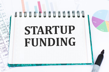 Text sign showing Startup Funding. Word for financial investment in the development of a new company Office Supplies Over Desk With Keyboard And Glasses And Coffee Cup For Working