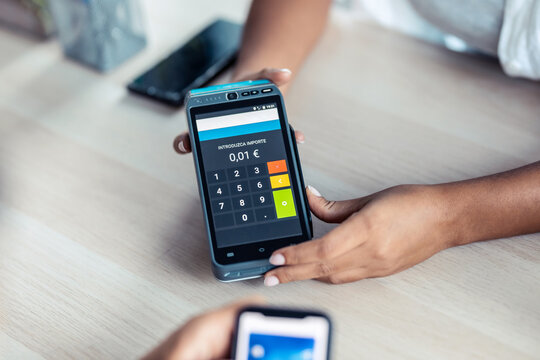 Female customer using her credit card to make payment with electronic reader in a shop.