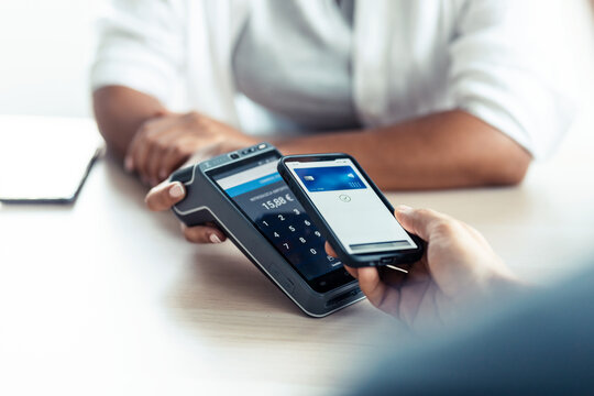 Female customer using her credit card to make payment with electronic reader in a shop.
