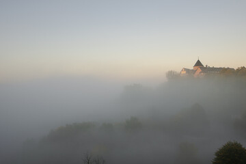 View to german palais called Waldeck in the morning with fog over the lake Edersee