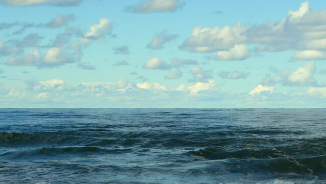 Landscape with calm ocean waves and blue sky with clouds. Cold sea in northern latitudes.