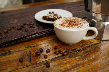 Hot cappuccino in white cup with wooden background,coffee is a popular drink all over the world.
