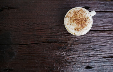 Hot cappuccino in white cup with wooden background,coffee is a popular drink all over the world.