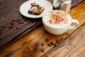 Hot cappuccino in white cup with wooden background,coffee is a popular drink all over the world.