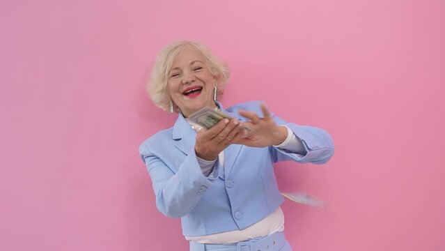 Close-up of an attractive, stylishly dressed woman in adulthood throws money away, spending it on a useless thing, an isolated background in the studio. happy woman