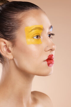 Beauty, woman and paint on face, makeup or creative art on studio background. Clown, fashion cosmetics or unique self expression, thinking female model from Canada with red lips and yellow eyeshadow.
