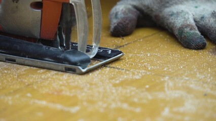 A worker cutting a sheet of fiberglass with an electric jigsaw.