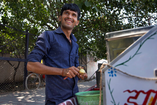 Portrait of a smiling male vendor peeling off potato