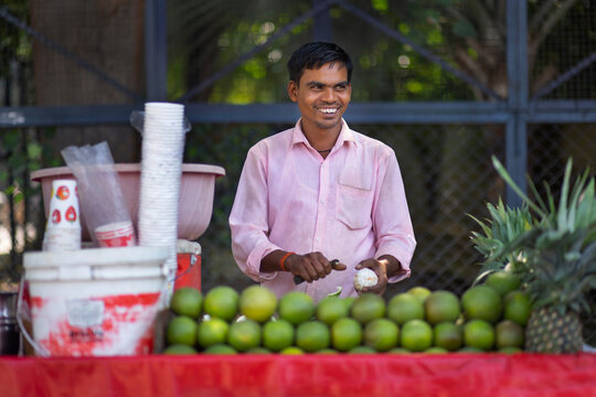 Male vendor peeling sweet lime at his roadside juice shop