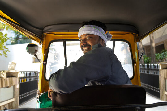 Portrait of a happy auto rickshaw driver looking back