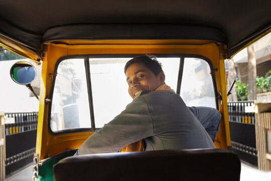 Portrait of a happy auto rickshaw driver looking back