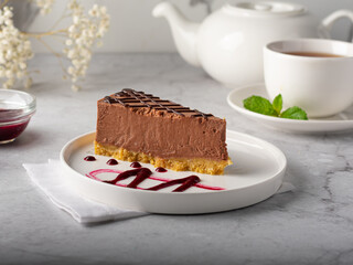chocolate cheesecake with chocolate glaze on white marble background.