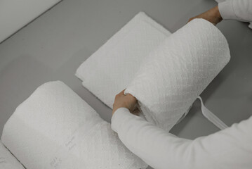 a female employee of a clothing workshop ties a roll of prepared white fabric; fabric preparation before sending for other production processes