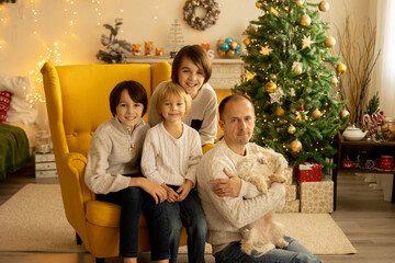 Happy family with three kids and dog, sitting at home at Christmas, cozy atmosphere