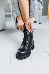 Slender female legs in black winter leather boots. Fashionable women's boots. Women's leather shoes.