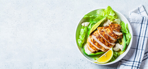 Grilled chicken breast salad with avocado and caesar dressing, top view, copy space. Keto diet food, balanced diet.