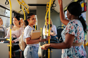Black woman and student talking on city bus