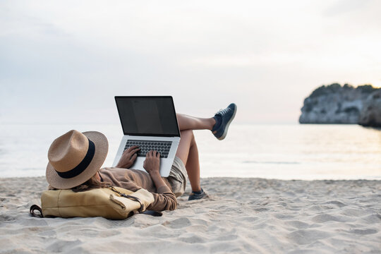 Young woman using laptop computer on beach, freelancer girl working remote, Freelance work, online learning, distant work concept.